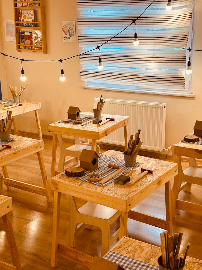 Warm classroom with wooden tables and crafts setup, ideal for creative workshops.